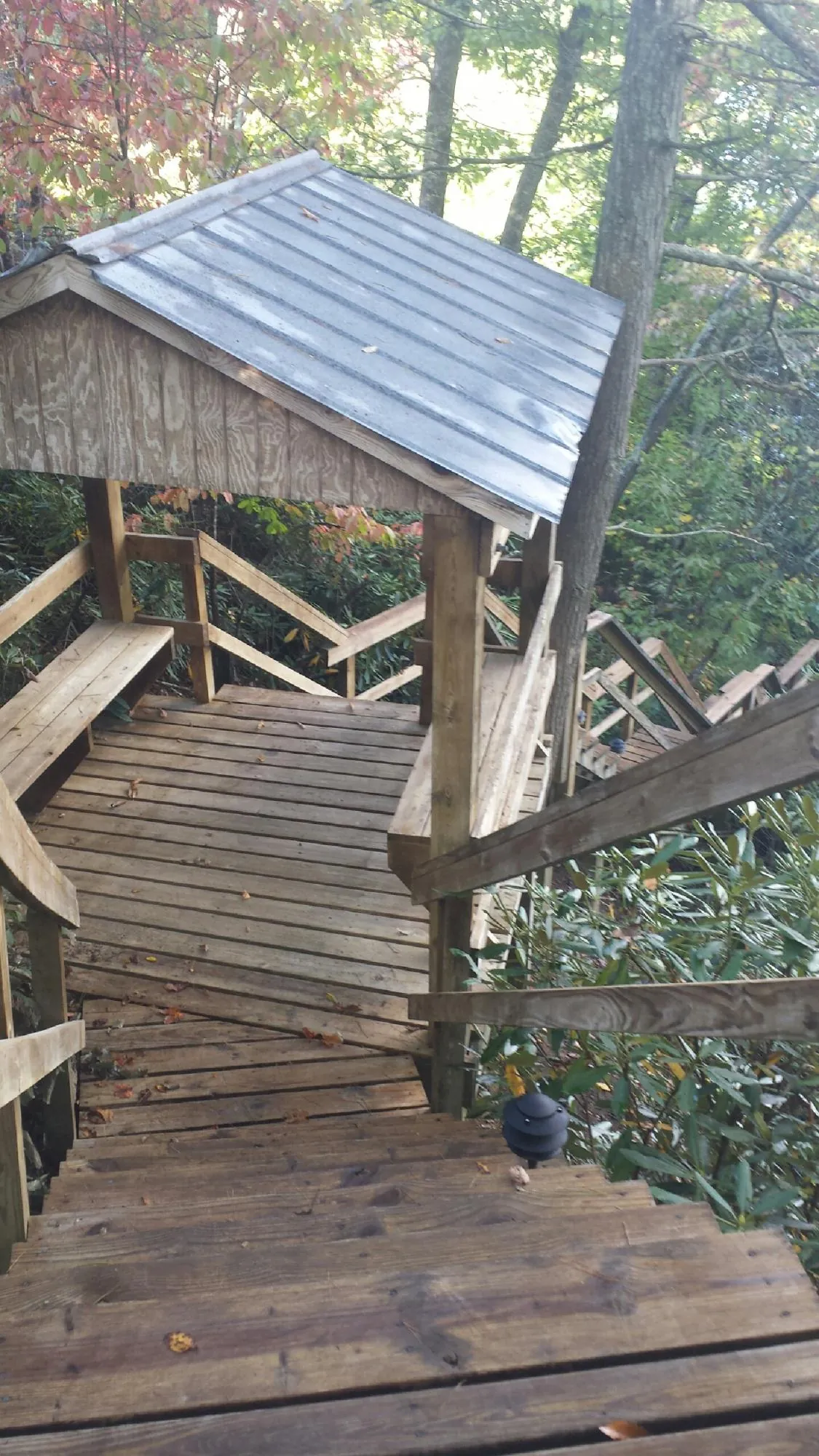 Metal roofed shelter over wooden steps on a wooded walkway — Skylight Repair & Installation work by our crew in Portage